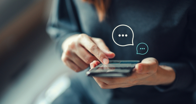 a woman's hands holding a mobile phone, showing chat bubbles