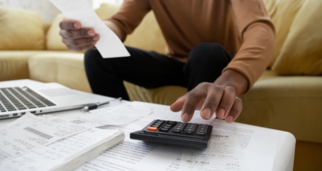 57% of over-55s struggling to clear mortgages before retirement a man looks at a coffee table covered with receipts and a calculator