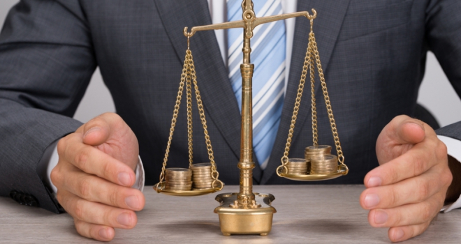 Adviser PII premiums rise by 17% in 2019: FCA pound coins money scales balance business man hands